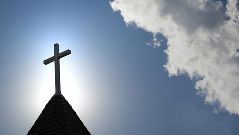 cross on top of church blue sky