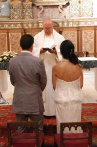 Sacraments A picture of a couple knelling down while getting wed before a priest.